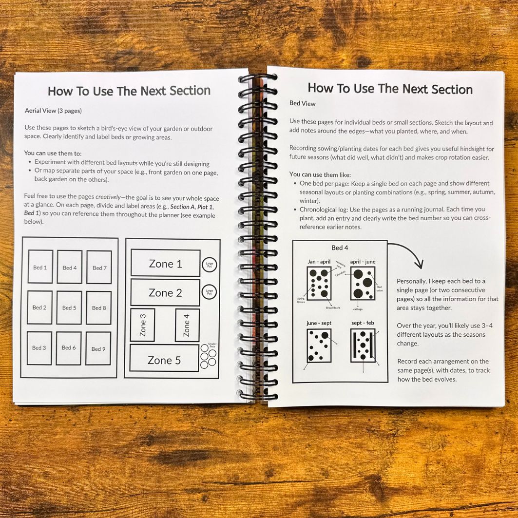 Open spiral-bound book with gardening planning pages on a wooden surface